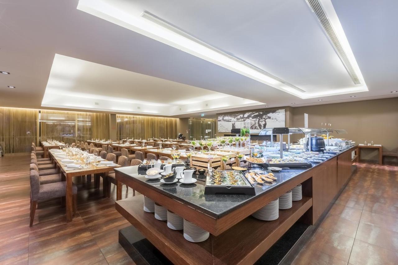 Ap Lago Montargil - Conference & Spa エクステリア 写真 The photo displays a spacious restaurant interior, featuring a well-organized dining area with multiple tables set for patrons. In the center, there is a large buffet station filled with an array of food items. The decor is modern and elegant, with w