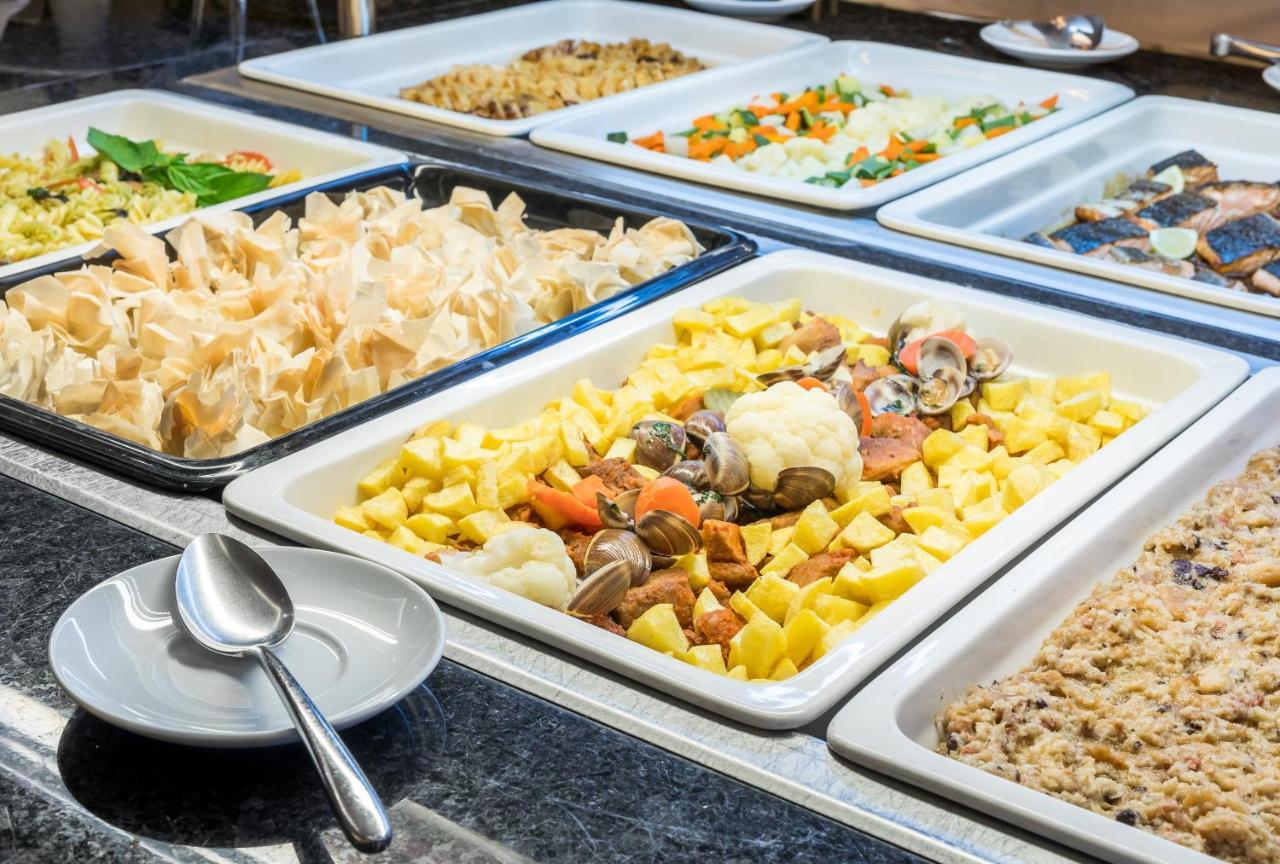 Ap Lago Montargil - Conference & Spa エクステリア 写真 The photo shows a buffet-style display of various dishes. There are several rectangular trays filled with different types of food. 

1. One tray contains a mix of vegetables and seafood, likely including potatoes and cauliflower.
2. Another tray hold