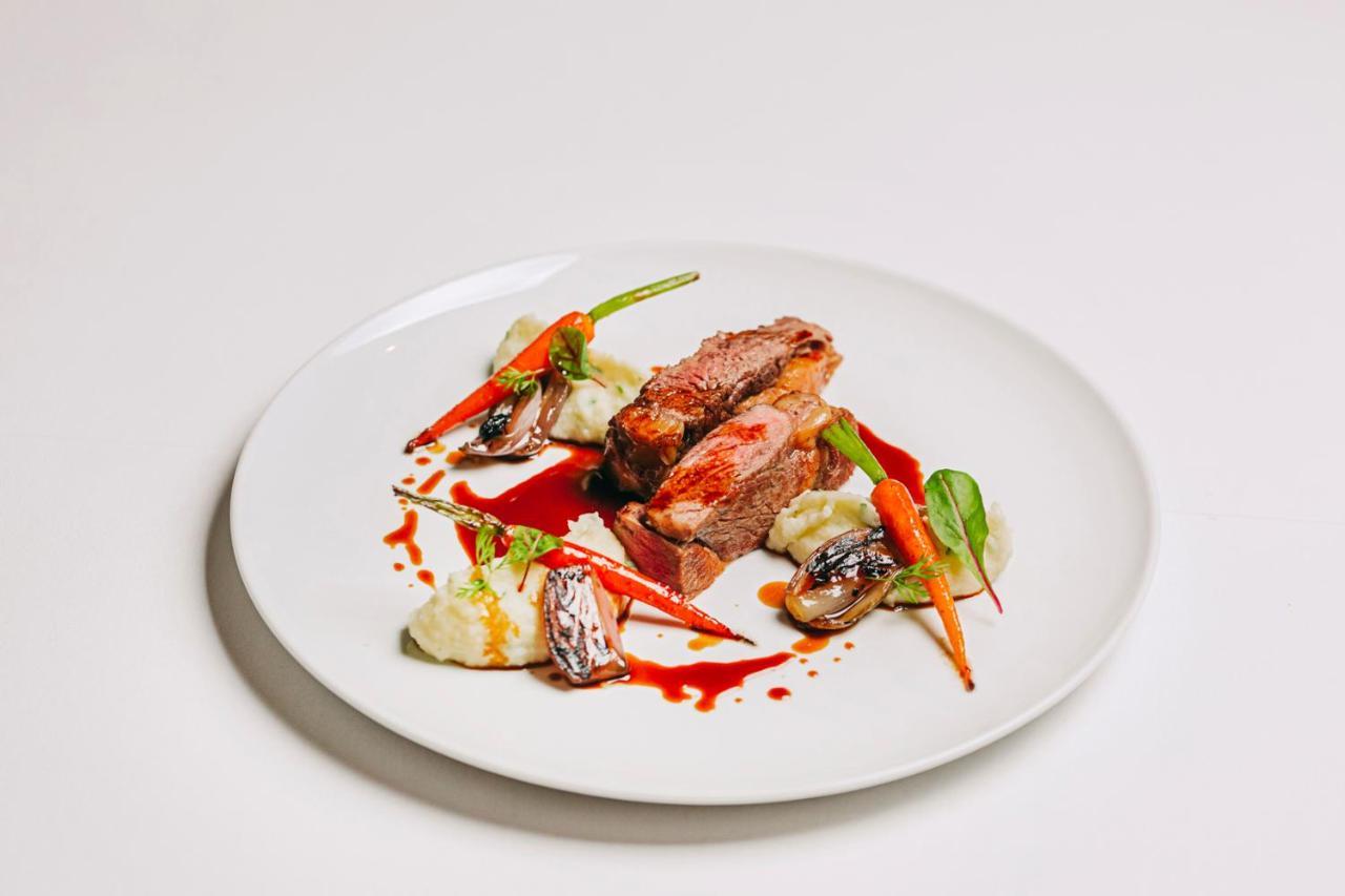 Ap Lago Montargil - Conference & Spa エクステリア 写真 The photo features a beautifully plated dish. At the center, there are slices of a tender meat, likely beef, showcasing a juicy pink interior. Accompanying the meat are several elements: vibrant orange carrots, perhaps roasted or glazed, and dollops 