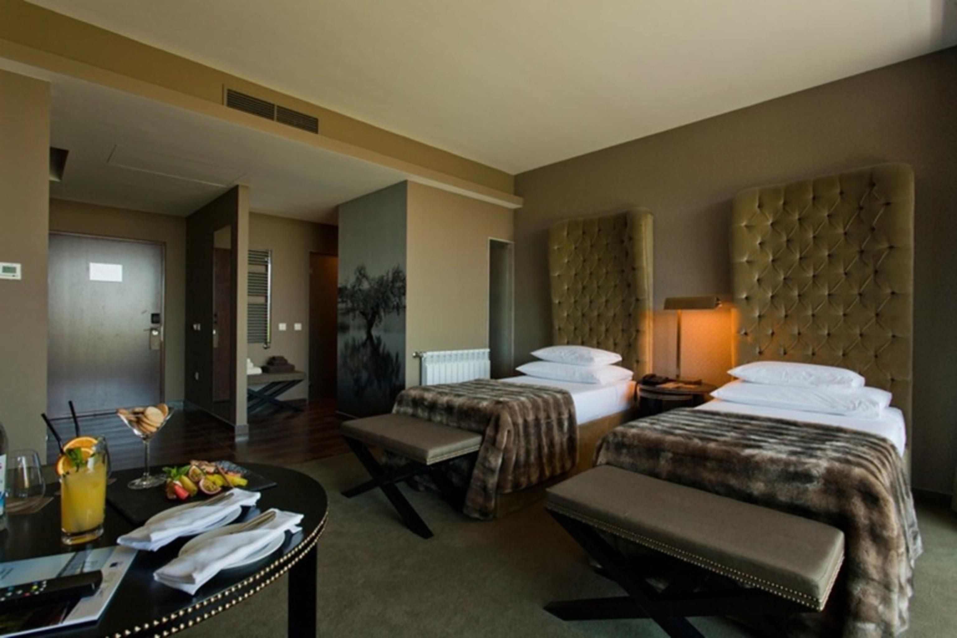 Ap Lago Montargil - Conference & Spa エクステリア 写真 The photo shows a stylish hotel room featuring two beds with plush, upholstered headboards. The room has a modern and elegant design, with earthy tones dominating the decor. A small round table is set up in the foreground, displaying a drink and some
