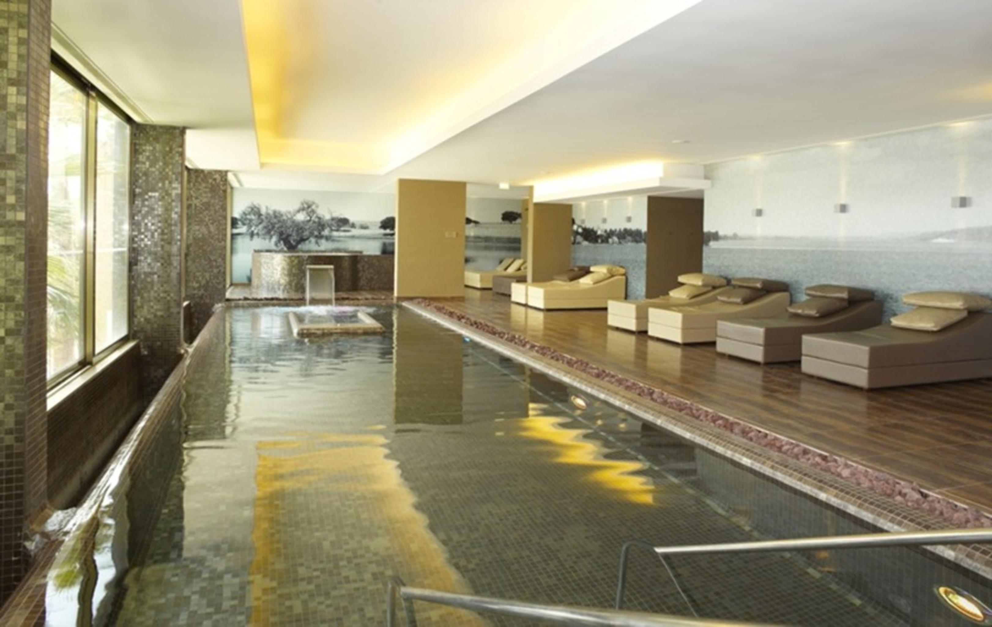 Ap Lago Montargil - Conference & Spa エクステリア 写真 The photo shows a modern, serene spa environment. There is a swimming pool with calm water, reflecting the surrounding decor. Along the sides, there are several comfortable lounge chairs arranged, perfect for relaxation. Large windows allow natural l