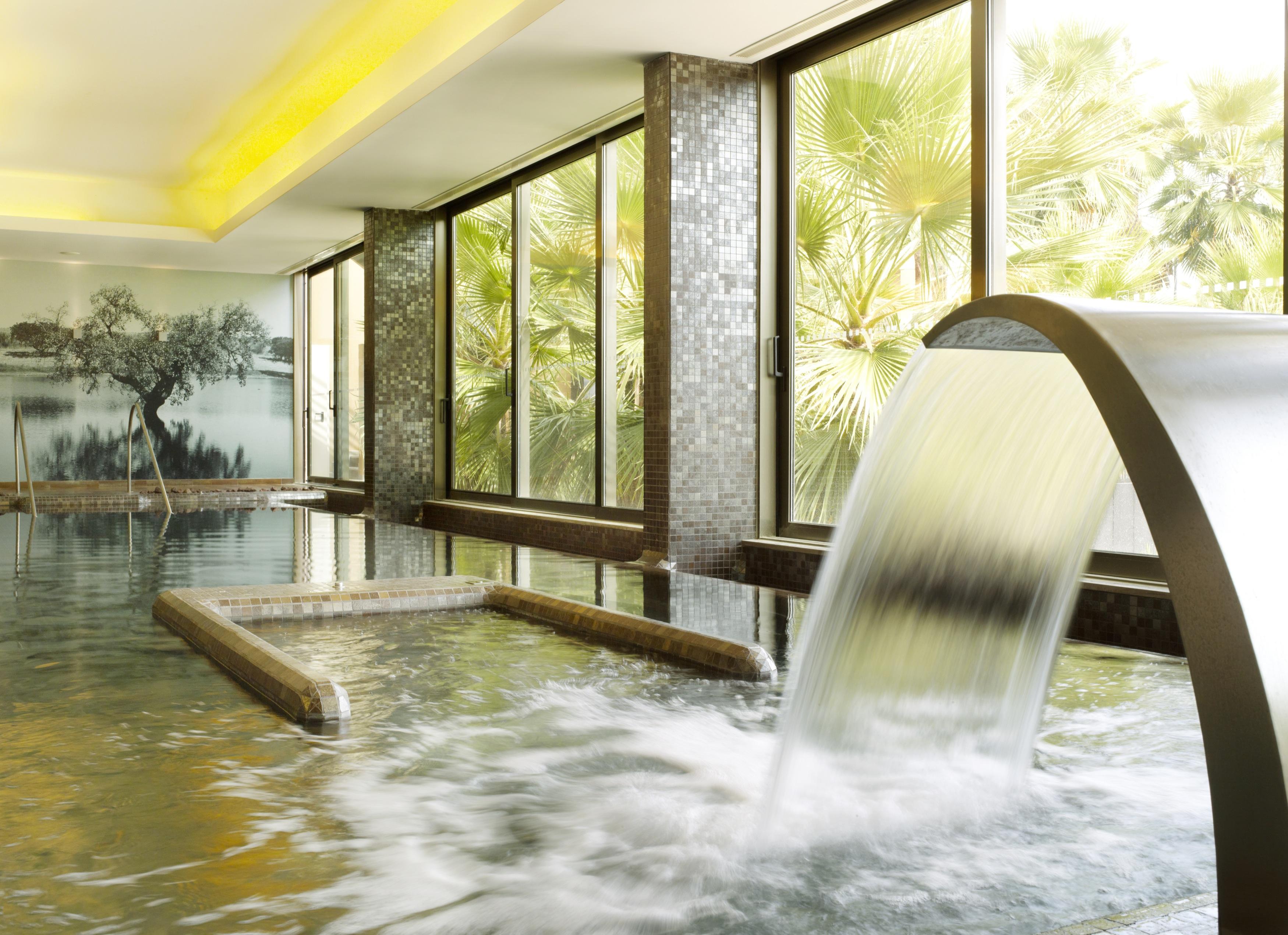 Ap Lago Montargil - Conference & Spa エクステリア 写真 The photo depicts a serene spa environment featuring a tranquil indoor pool area. There is a sleek, modern water feature that spills water gracefully into the pool. Large windows allow natural light to flood the space, showcasing views of lush greene